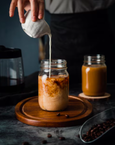 Milk being poured into a glass coffee cup.